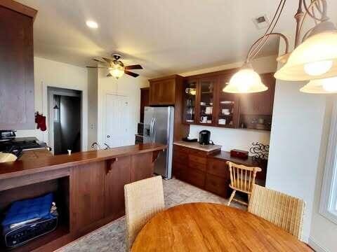 kitchen featuring pendant lighting, ceiling fan, and stainless steel fridge with ice dispenser