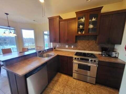 kitchen featuring appliances with stainless steel finishes, sink, backsplash, and kitchen peninsula