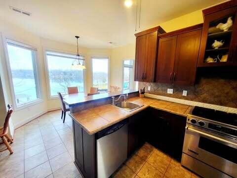 kitchen with stainless steel appliances, kitchen peninsula, sink, and backsplash