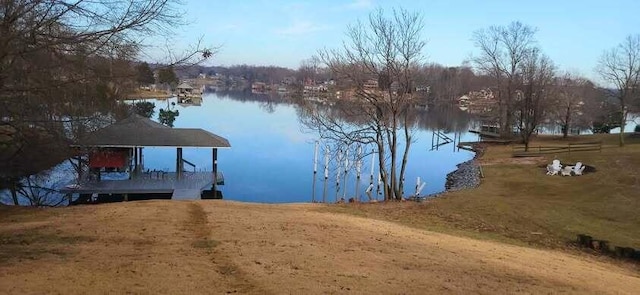 view of dock with a lawn and a water view