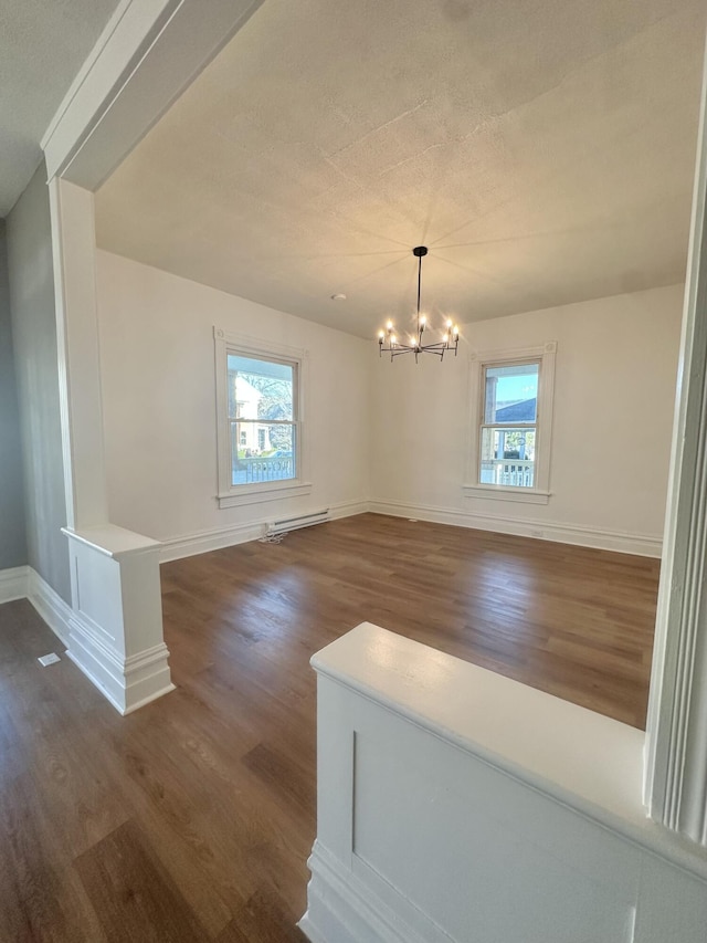 unfurnished dining area with dark wood finished floors, a wealth of natural light, and an inviting chandelier