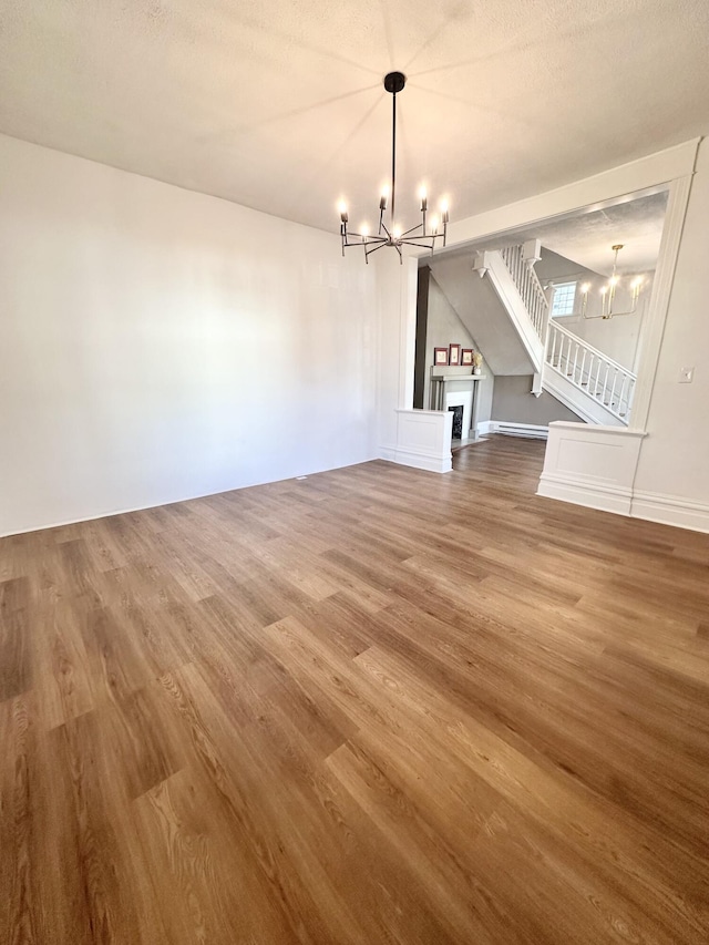 unfurnished living room featuring a fireplace, a notable chandelier, and wood finished floors