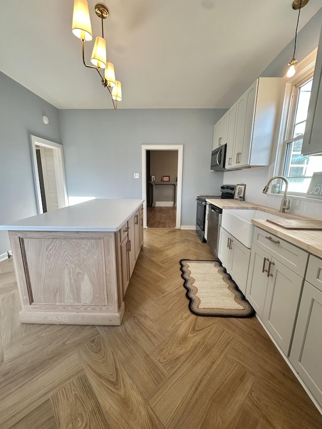 kitchen featuring pendant lighting, light countertops, appliances with stainless steel finishes, white cabinets, and a kitchen island