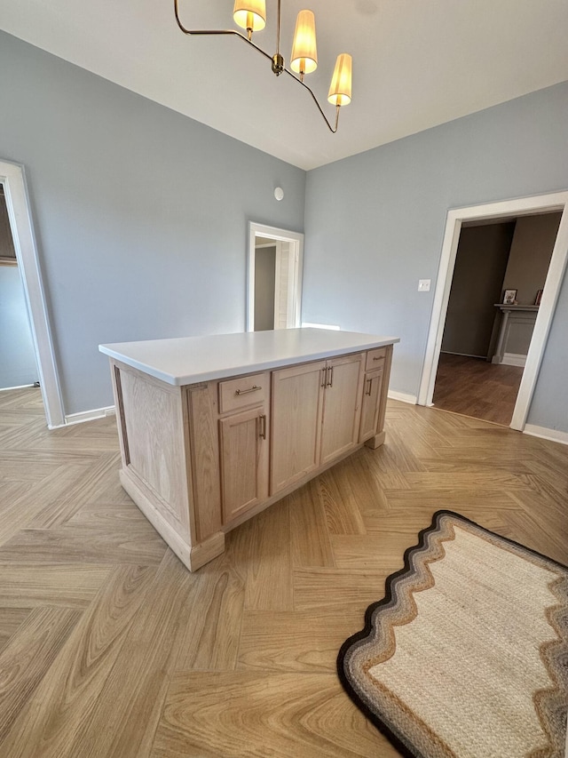 kitchen featuring a kitchen island, light countertops, hanging light fixtures, and light brown cabinets