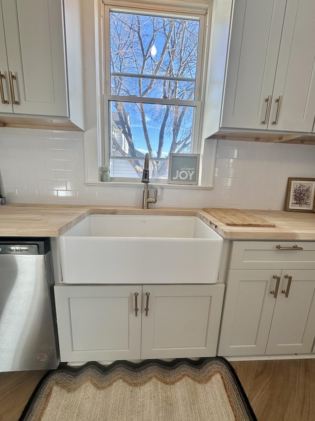 kitchen featuring dishwasher, backsplash, a sink, and wooden counters