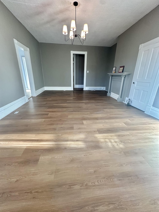 unfurnished dining area with baseboards, a textured ceiling, light wood-type flooring, and a notable chandelier