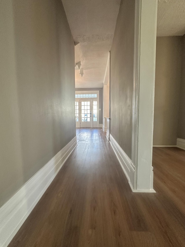 corridor featuring dark wood-style floors and baseboards