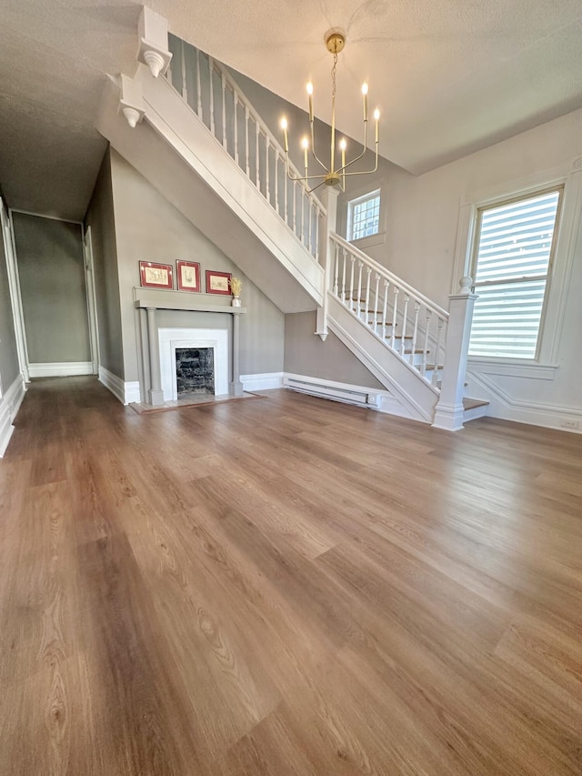 unfurnished living room with a fireplace, wood finished floors, a chandelier, baseboards, and stairs