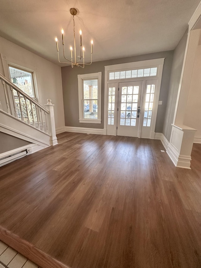 unfurnished living room with stairs, a baseboard radiator, an inviting chandelier, and wood finished floors