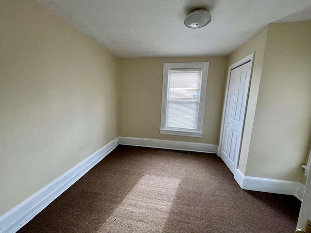 unfurnished bedroom featuring a closet and dark colored carpet