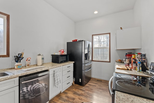 kitchen featuring white cabinetry, light hardwood / wood-style floors, and appliances with stainless steel finishes