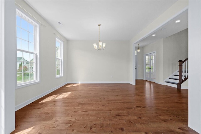 empty room with dark wood-type flooring and an inviting chandelier