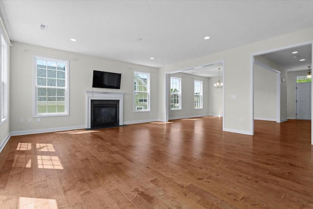 unfurnished living room with hardwood / wood-style flooring and a notable chandelier