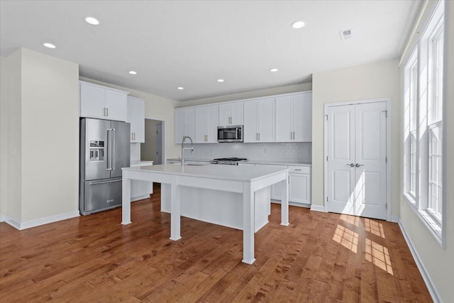 kitchen featuring a center island with sink, white cabinets, and appliances with stainless steel finishes