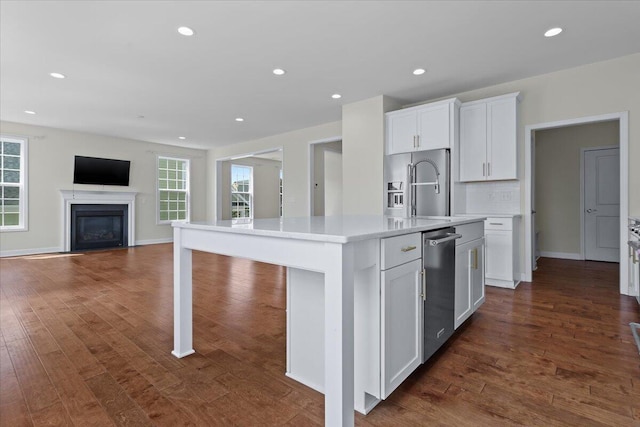 kitchen with plenty of natural light, dark hardwood / wood-style floors, a center island with sink, and white cabinets