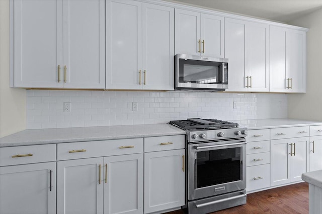 kitchen with white cabinetry, appliances with stainless steel finishes, dark hardwood / wood-style floors, and backsplash