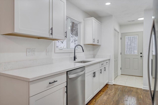 kitchen with stainless steel appliances, wood-type flooring, sink, and white cabinets