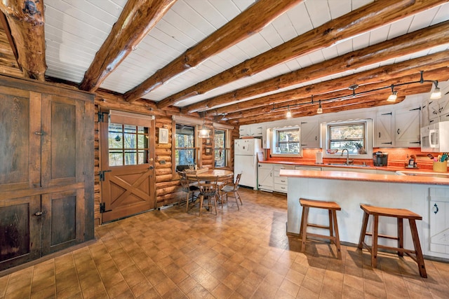 kitchen featuring white cabinetry, a kitchen breakfast bar, kitchen peninsula, white appliances, and beam ceiling