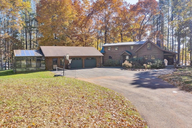 cabin with a garage, a front lawn, and a sunroom