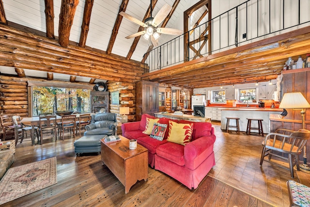 living room with ceiling fan, hardwood / wood-style flooring, a wealth of natural light, and beamed ceiling