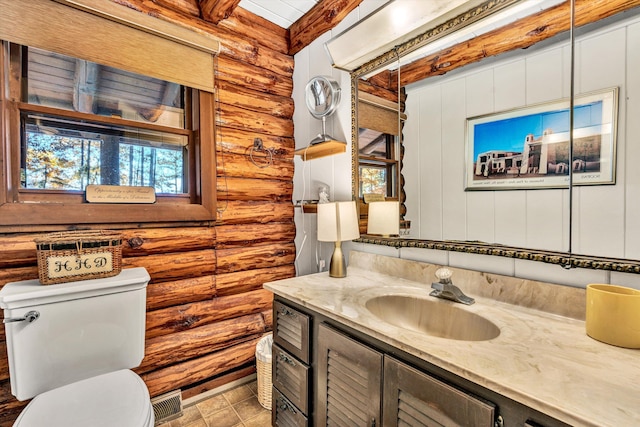 bathroom with vanity, log walls, and toilet