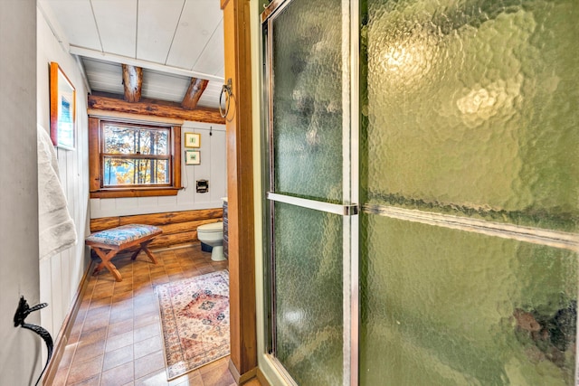 bathroom featuring toilet, a shower with shower door, wooden ceiling, wooden walls, and beamed ceiling