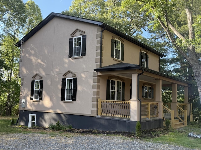 view of side of home with covered porch and stucco siding