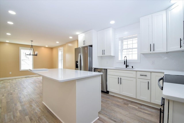 kitchen with light wood-style floors, a center island, appliances with stainless steel finishes, and a sink