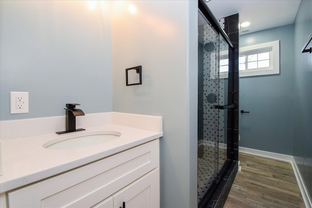 full bathroom with a shower stall, baseboards, wood finished floors, and vanity