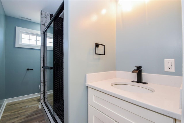 full bath with vanity, wood finished floors, visible vents, and a shower stall