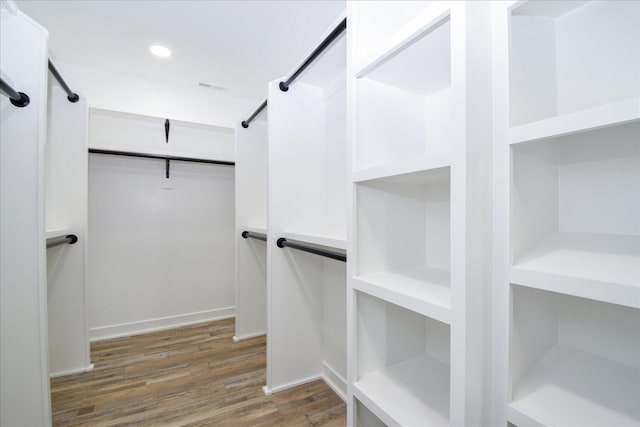 walk in closet with a barn door and wood finished floors