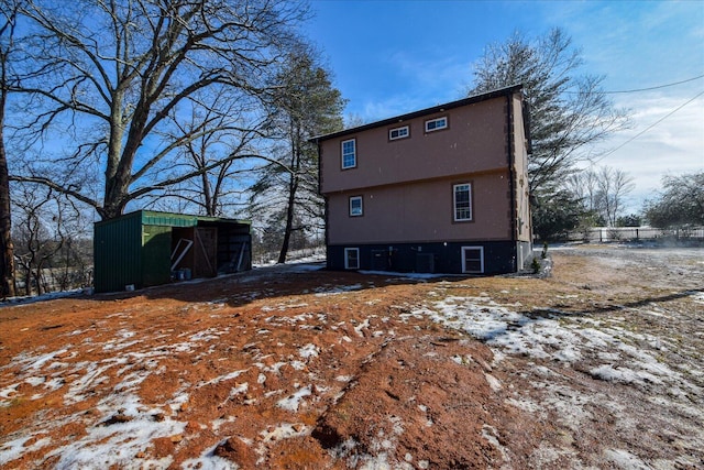 snow covered property with an outbuilding