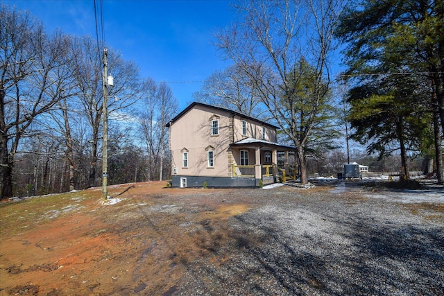 view of side of home featuring a porch, driveway, and stucco siding