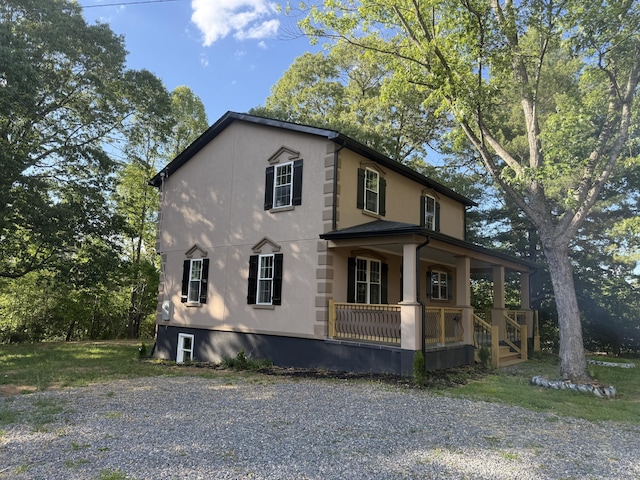 view of side of property featuring covered porch and stucco siding