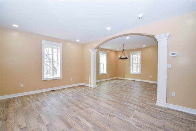 spare room with light wood-style flooring, ornate columns, baseboards, a chandelier, and recessed lighting