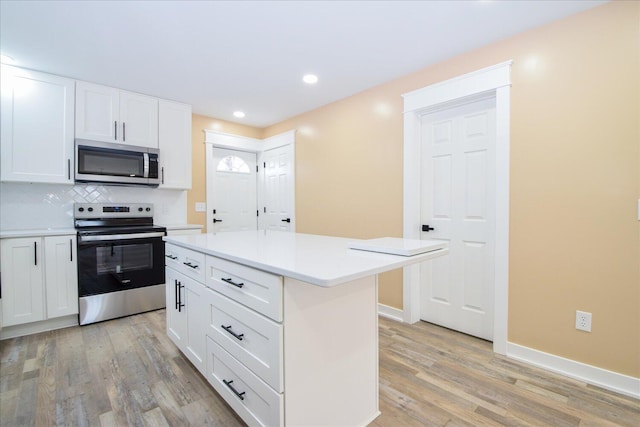 kitchen with stainless steel appliances, a kitchen island, light countertops, and white cabinetry