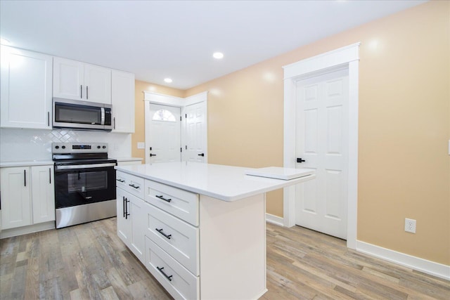 kitchen featuring light wood-style flooring, stainless steel appliances, white cabinets, light countertops, and tasteful backsplash