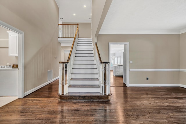 stairs with hardwood / wood-style flooring, crown molding, and washer / clothes dryer