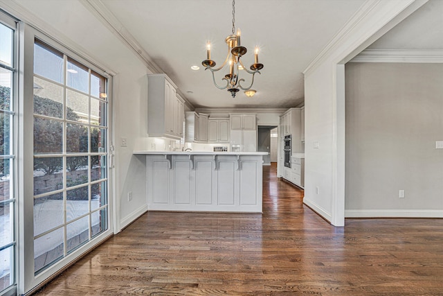 kitchen featuring a breakfast bar, decorative light fixtures, white cabinetry, ornamental molding, and kitchen peninsula