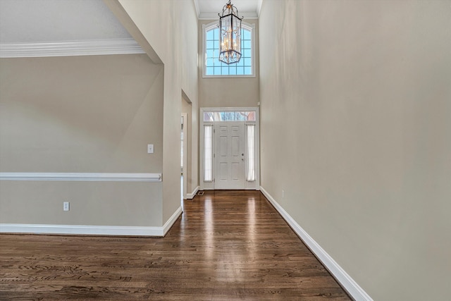 foyer entrance with ornamental molding, dark hardwood / wood-style floors, a chandelier, and a towering ceiling