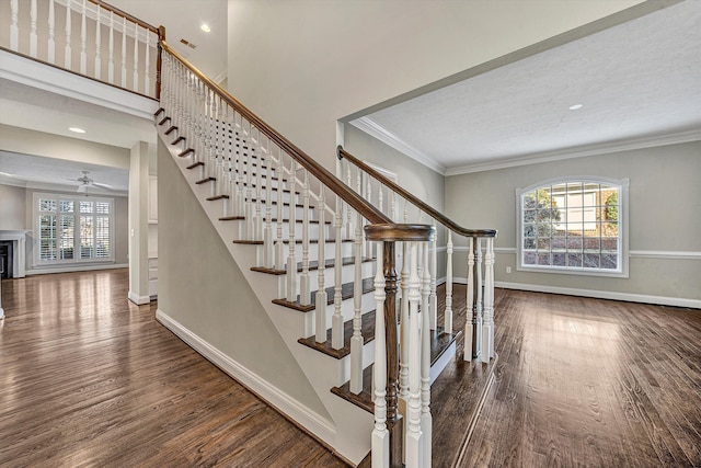 stairs featuring a wealth of natural light, wood-type flooring, and ornamental molding