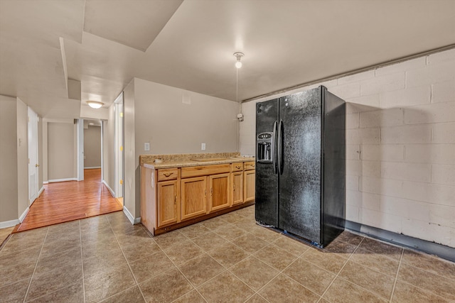 kitchen featuring baseboards, tile patterned flooring, and black fridge with ice dispenser