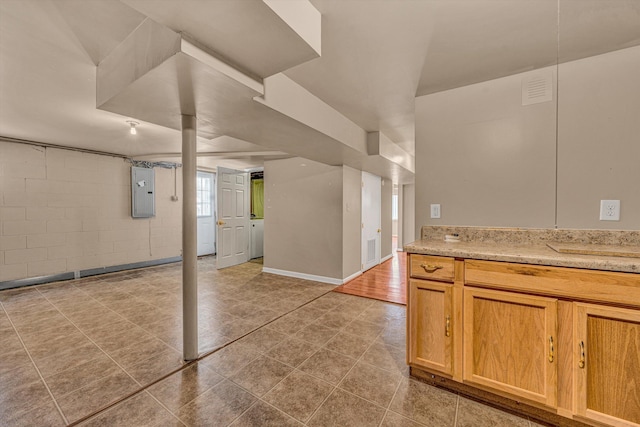 interior space featuring concrete block wall, light countertops, electric panel, and baseboards