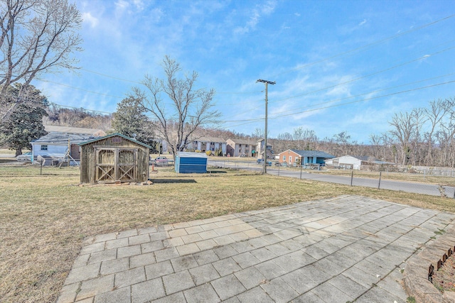 view of yard with fence, a storage unit, and an outbuilding