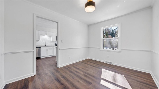 empty room with dark wood-style floors, baseboards, visible vents, and ornamental molding