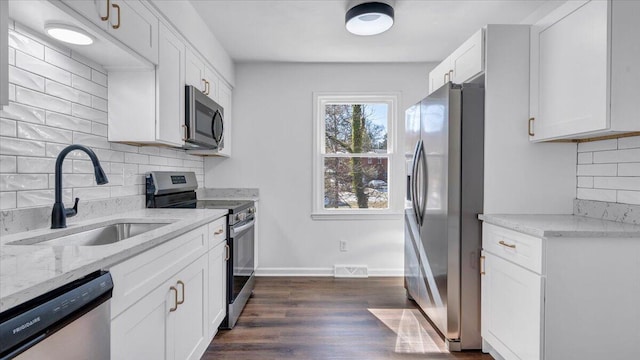 kitchen featuring light stone counters, visible vents, appliances with stainless steel finishes, white cabinetry, and a sink