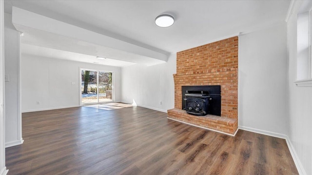 unfurnished living room with dark wood-style floors, a wood stove, and baseboards