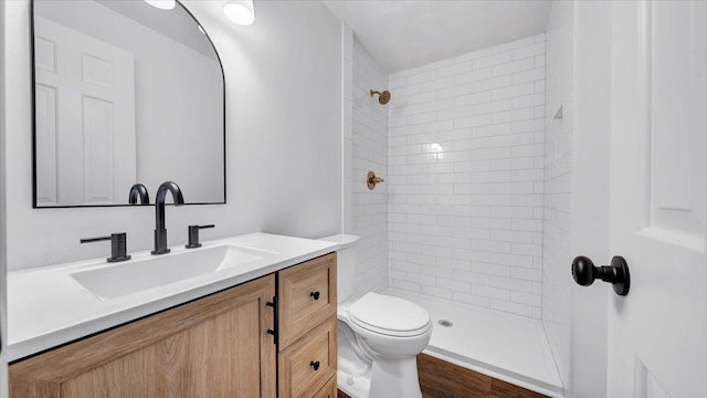 full bath with toilet, a tile shower, and vanity