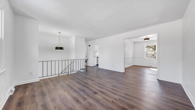 unfurnished room with dark wood-style floors, visible vents, and baseboards