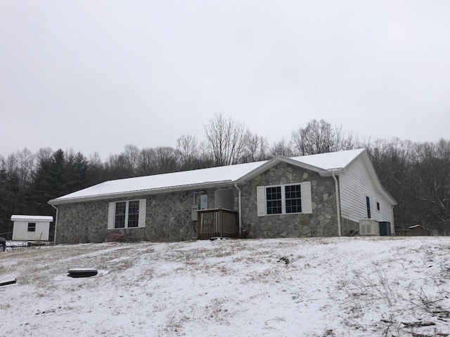 single story home featuring cooling unit and stone siding